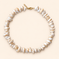 שרשרת SHELL AURA מצדפים בגווני שמנת ובז׳, עם סוגר בציפוי זהב, על רקע שמנת
