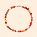 שרשרת SUNSET MOSAIC בשילוב אבני עין החתול, אגת, ג׳ייד, צדפים וחרוזי זכוכית בגווני אדום וכתום על רקע שמנת